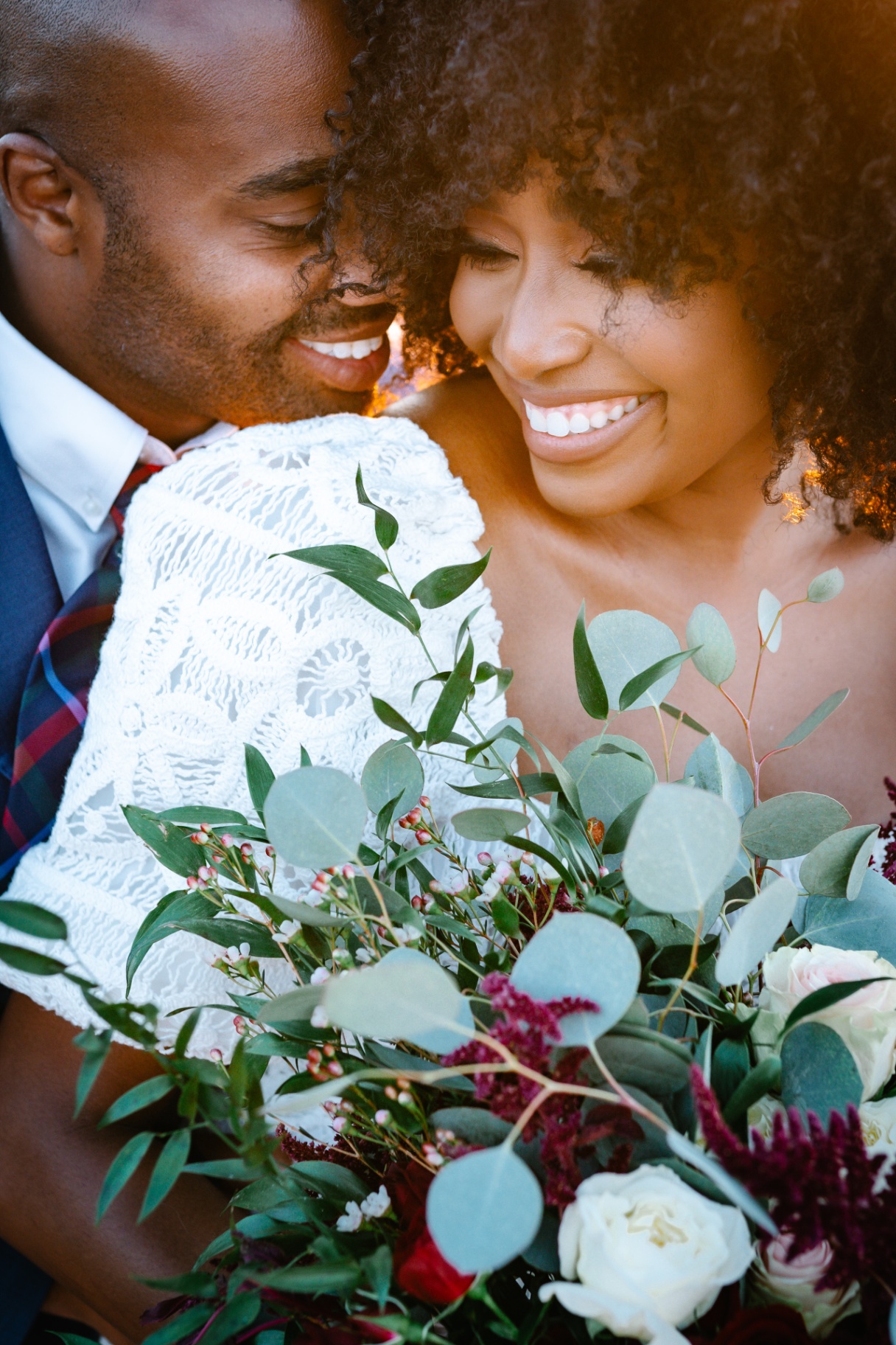 Bride and groom sharing a quiet laugh with bouquet