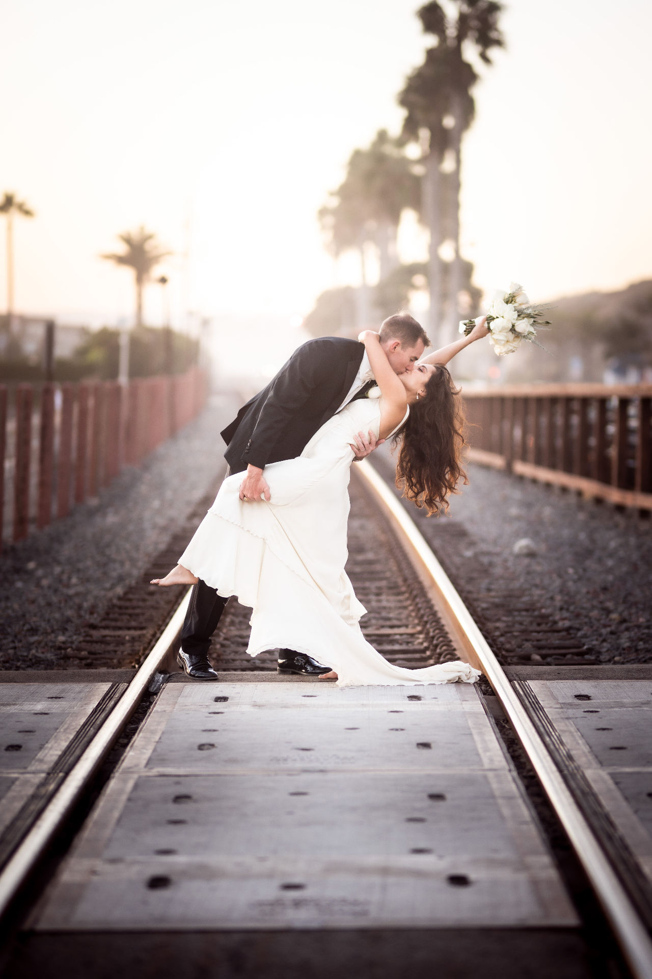 Bride and groom dip kiss at sunset